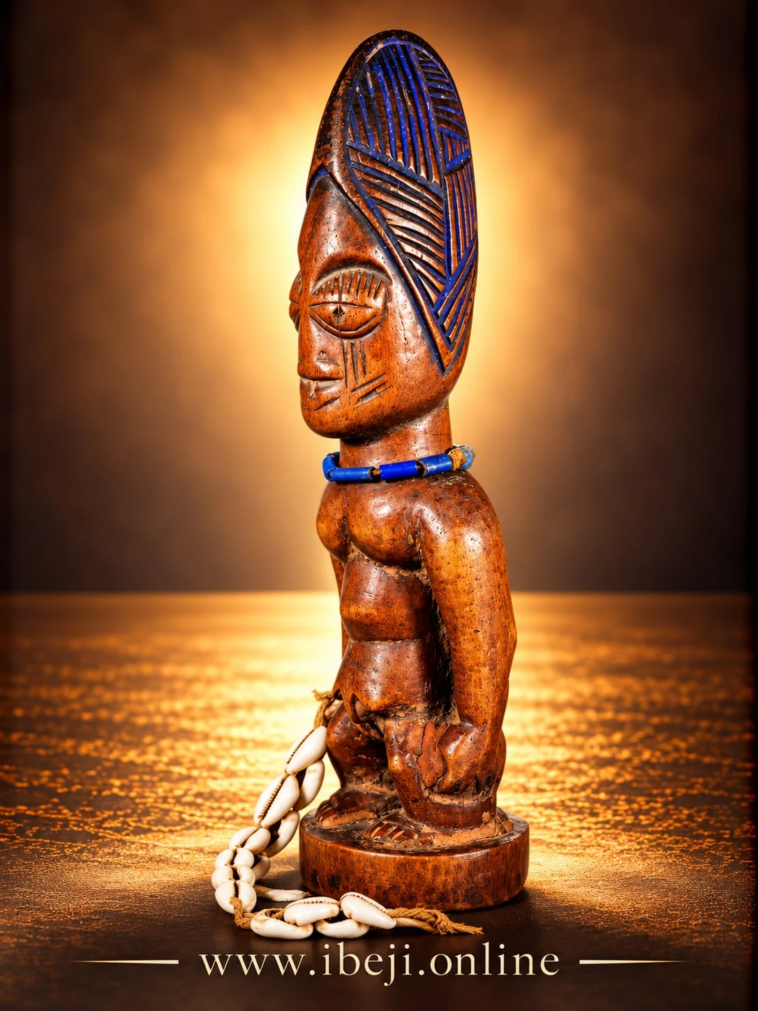 Figura Ibeji de madera con cofia azul y cauris alrededor del pedestal