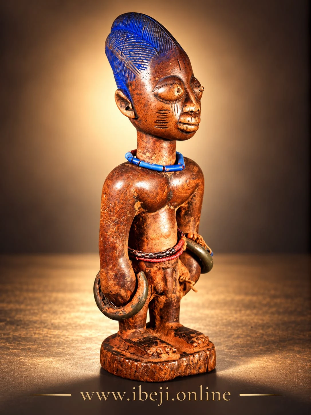Figura Ibeji de madera vista en tres cuartos, con cofia azul y collar